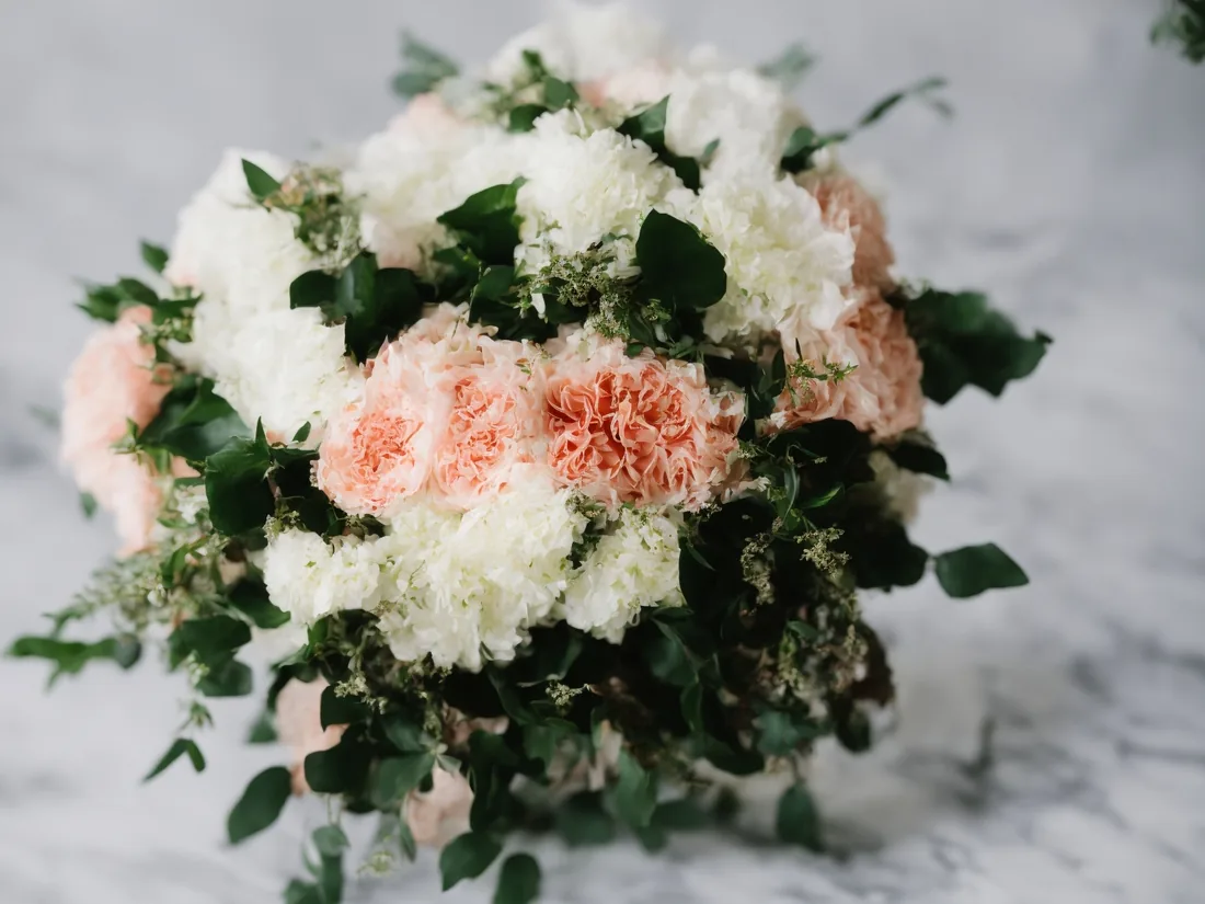 Blush and white floral centerpiece arranged on an elegant wedding table